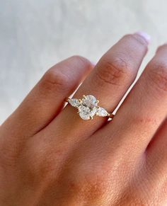 a woman's hand with a diamond ring on top of her finger and an engagement band