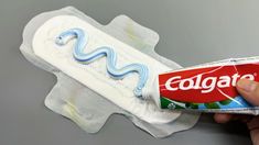 a hand holding a package of colgate toothpaste in it's packaging