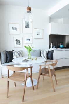 a dining room table with chairs around it and pictures on the wall in the background