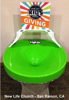 a green toilet sitting on top of a wooden floor next to a sign with the words giving