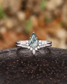 an engagement ring with a pear shaped aqua blue diamond surrounded by small white diamonds on a rock