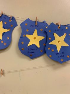 three police badges are hanging from clothes pins on a line in the shape of stars