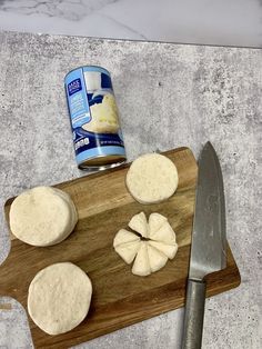 a cutting board topped with cut up cheese next to a knife and can of milk