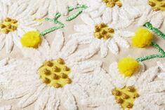 yellow flowers on white fabric with green stems and leaves in the center are crocheted