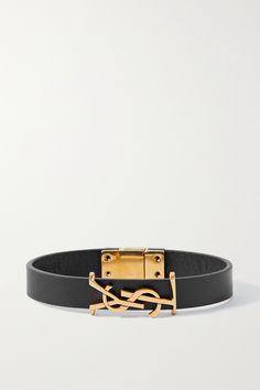 SAINT LAURENT's slim 'Opyum' bracelet has been made in Italy from leather and threaded with a gilded 'YSL' logo plaque. It's equipped with a magnetic fastening, so you'll easily be able to adjust the fit to your wrist. It would make a lovely gift as the smart presentation box will feel like such a joy to open. Elegant Leather Bracelets With Gold Clasp, Elegant Leather Bracelet With Gold Clasp, Yellow Gold Leather Bracelet Gift, Yellow Gold Leather Bracelet As Gift, Adjustable Leather Bracelet With Gold Clasp, Formal Yellow Gold Leather Bracelets, Yellow Gold Leather Bracelets For Gift, Adjustable Yellow Gold Leather Bracelet, Designer Black Leather Strap Bracelets