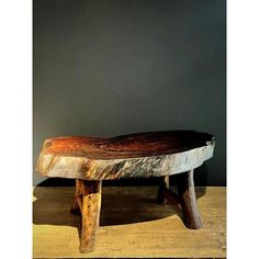 a wooden bench sitting on top of a hard wood floor next to a gray wall