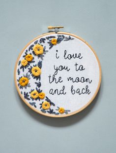 a hand embroidered hoop with yellow flowers and the words i love you to the moon and back