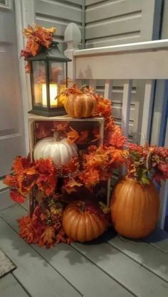 pumpkins and gourds are arranged on a porch