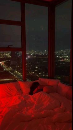 a person laying on a bed in front of a window with red light coming from it