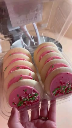 a person is holding up some cookies in a plastic container with sprinkles on them