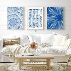 a living room with white furniture and blue artwork on the wall above the coffee table