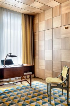 a chair and desk in a room with wood paneling on the wall behind it