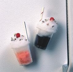 two drinks are sitting next to each other on a white surface with red and black straws