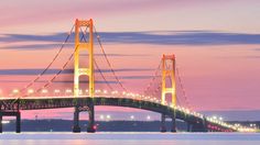 a bridge that is over water with lights on at the top and bottom of it