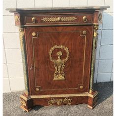 an antique wooden cabinet with gold decorations on the front and sides, painted in dark brown