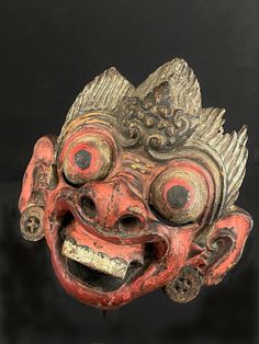 an old mask with red eyes and hair on it's head is displayed in front of a black background