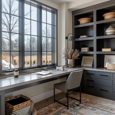 a home office with black bookcases and large windows