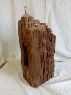 a wooden sculpture made to look like a castle on top of a white sheeted surface