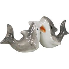 two white ceramic dolphins with orange beaks on their heads, one is facing the other