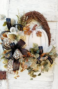 a white pumpkin wreath with black ribbon and leopard print bow hanging on the front door