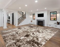 a large living room with white walls and wooden floors, an area rug on the floor