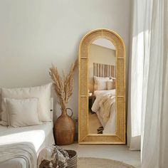 a room with a bed, mirror and pillows on the floor in front of it