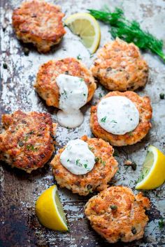 crab cakes on a baking sheet with lemon wedges and dill garnish