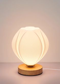 a white lamp sitting on top of a wooden table next to a light bulb in the shape of a flower