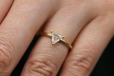 a woman's hand with a diamond ring on top of her finger, showing the side view