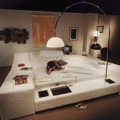 a woman laying on top of a bed in a room with lots of pictures and lights