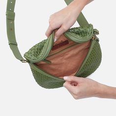 a woman is holding her purse in one hand and pulling the strap out from another