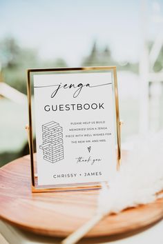 a guest book is sitting on top of a wooden table with a feather in it