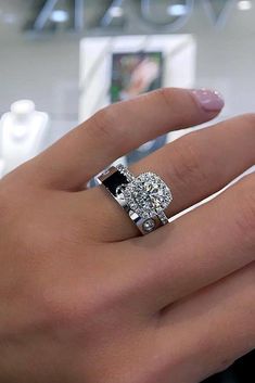 a woman's hand with a diamond and black stone ring on top of her finger