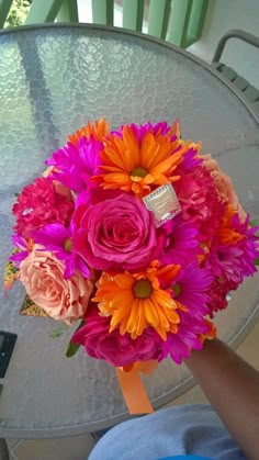 a bouquet of flowers sitting on top of a table next to a person's hand