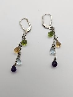 "925 Silver Amethyst, Peridot, Citrine, and Blue Topaz Briolette Multi-gem Dangle Earrings  Item w#2825 These Vintage 925 Silver Briolette Cut Gemstone Dangle Earrings are a stunning showcase of vibrant colors and classic elegance. Crafted with precision, each earring features briolette-cut gemstones in amethyst, citrine, peridot, and blue topaz, creating a harmonious blend of hues. Measuring 2 inches long, these dangle earrings offer a graceful and elongated silhouette, perfect for adding a tou Teardrop Multi-stone Earrings As A Gift, Dangle Multi-stone Earrings For Gifts, Long Drop Multi-stone Earrings For Gift, Amethyst Multi-stone Briolette Earrings, Amethyst Multi-stone Dangle Jewelry, Amethyst Multi-stone Drop Earrings, Amethyst Multi-stone Earrings As Gift, Silver Multi-stone Briolette Gemstones, Teardrop Multi-stone Amethyst Earrings