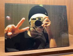 a person taking a photo with a camera on a wooden shelf in front of a mirror