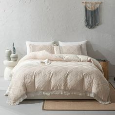 a white bed sitting in a bedroom next to a wooden table and vases on top of a rug