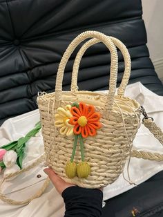 a hand holding a straw bag with flowers on it