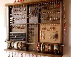 a wall mounted jewelry organizer with lots of earrings on it's sides and hanging from the ceiling