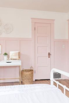 a bedroom with pink walls, white furniture and a wicker basket on the bed