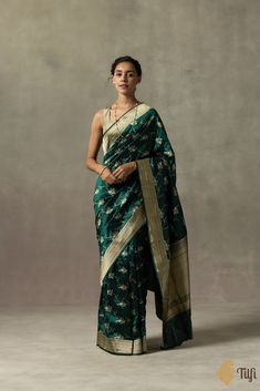 "\nA lustrous bottle green saree\u00a0adorned with a whimsical aadha jangla in the body and finished with\u00a0a rich dose of zari in the borders and pallu.\u00a0\n\n\n\nColor\u00a0- A\u00a0charming shade of\u00a0Bottle Green\n\nTechnique\u00a0- An enduring Kadwa weave. The elaborate and laborious Kadwa (Kadhua) technique involves hand-weaving each motif separately. It takes longer on the handloom, but makes a more robust pattern, which stands out on the fabric.\u00a0\n\nFabric\u00a0- Soft as butter, pure Katan silk\n\nTilfi Promise\u00a0- Pure. Handloom. Banaras.\n\nNote\u00a0- The saree comes with its own blouse piece. The\u00a0model is wearing a separate blouse for styling purposes.\n\n\u00a0\nSince this product is handwoven, there might be slight irregularities. But don't you think the Green Pre-draped Saree With Meenakari For Puja, Festive Green Pre-draped Saree With Zari Weaving, Green Semi-stitched Pre-draped Saree With Meenakari, Green Bollywood Pre-draped Saree With Meenakari, Traditional Dark Green Wear With Dupatta, Festive Green Paithani Silk Pre-draped Saree, Dark Green Traditional Wear With Dupatta For Festive Occasions, Festive Dark Green Traditional Wear With Dupatta, Dark Green Bollywood Dupatta With Cutdana