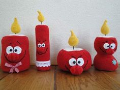 three crocheted candles with faces on them sitting on a wooden table next to each other