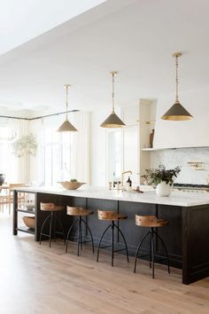 a kitchen with black and white counter tops and wooden stools in front of an island