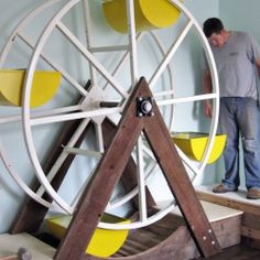 a man standing on top of a wooden table next to a yellow and white wheel