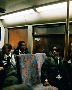 some people sitting on a bus and one is wearing a black jacket