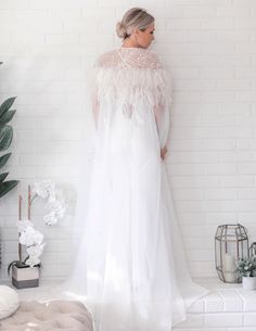 "It isn't enough to have feathers, you must dare to fly...." Add a touch of glamour to your bridal gown with this stunning Floor Length Tulle Beaded Cape with Ostrich Feather is a striking ivory color. With it’s floor length style, this ostrich feather statement piece is ideal for brides who are wanting something fabulous and show stopping on their wedding day. Hand Dyed Luxurious Ostrich Feather Cape Veil Clear Snap front closure Floor length style design with rounded front Made from Ethically White Ostrich Feather Wedding Dress, Elegant Feather-trim Wedding Gown, Elegant Wedding Gown With Feather Trim, Elegant Wedding Gown With Feathers, White Feathered Dresses For Wedding, Cape Veil, Feather Cape, Beaded Cape, Ostrich Feather