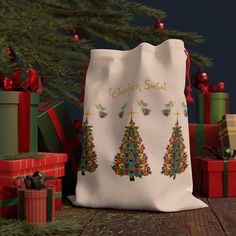 a white bag sitting on top of a wooden table next to presents and christmas trees