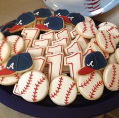 cookies decorated with baseballs and numbers are on a platter next to a plate