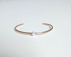 Simple, timeless, clean and beautiful! This pearl cuff bracelet is simply gorgeous. Each pearl is hand-drilled and sits very pretty along the top of this minimalist design. You can choose from 14kt gold fill, 14kt rose gold fill or sterling silver. Each genuine pearl is approximately 6mm in diameter. You can select from small, medium and large according to your wrist size. Your bracelet will arrive in a gift box with bow. Classic Cuff Bracelets For Wedding, Classic Pearl Bangle For Weddings, Minimalist Cuff Bracelet For Wedding, Classic Adjustable Cuff Bracelet For Wedding, Classic Rose Gold Pearl Bracelet For Wedding, Dainty Adjustable Cuff Bracelet For Anniversary, Classic White Cuff Bracelet For Wedding, Classic Cuff Wedding Jewelry, Dainty Bangle Cuff Bracelet For Anniversary