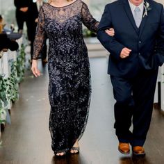 a man and woman are walking down the aisle at their wedding ceremony in an elegant black dress